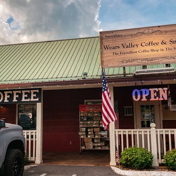 Wears Valley Coffee & Snack Co. storefront with "Coffee" and "Open" signs, an American flag, and parked cars.