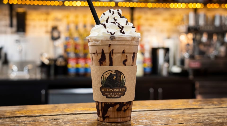 A chocolate frappe with whipped cream and chocolate drizzle, featuring a Wears Valley Coffee & Snack Company sleeve.