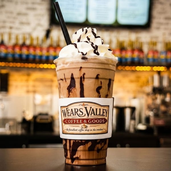 A Wears Valley Coffee & Goods iced mocha with whipped cream and chocolate drizzle on a counter.